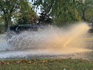 Water splashes around a car being driven through a water puddle.